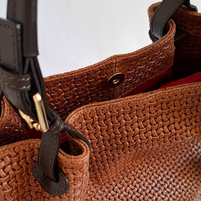 Close up of the Elegant and Luxurious gold tone magnetic closure button and details of the woven Leather and leather handles of the TL Keyluck Tote Bag in cognac leather by Montipi Australia with luxurious gold tone hardware signature of premium designer bag