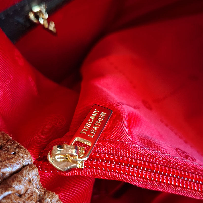 Close up of the Luxurious red interior design and gold tone hardware of the branded zip closure of the TL Keyluck Tote Bag in cognac leather by Montipi Australia with branded red interior and large organised compartment signature of premium designer bag