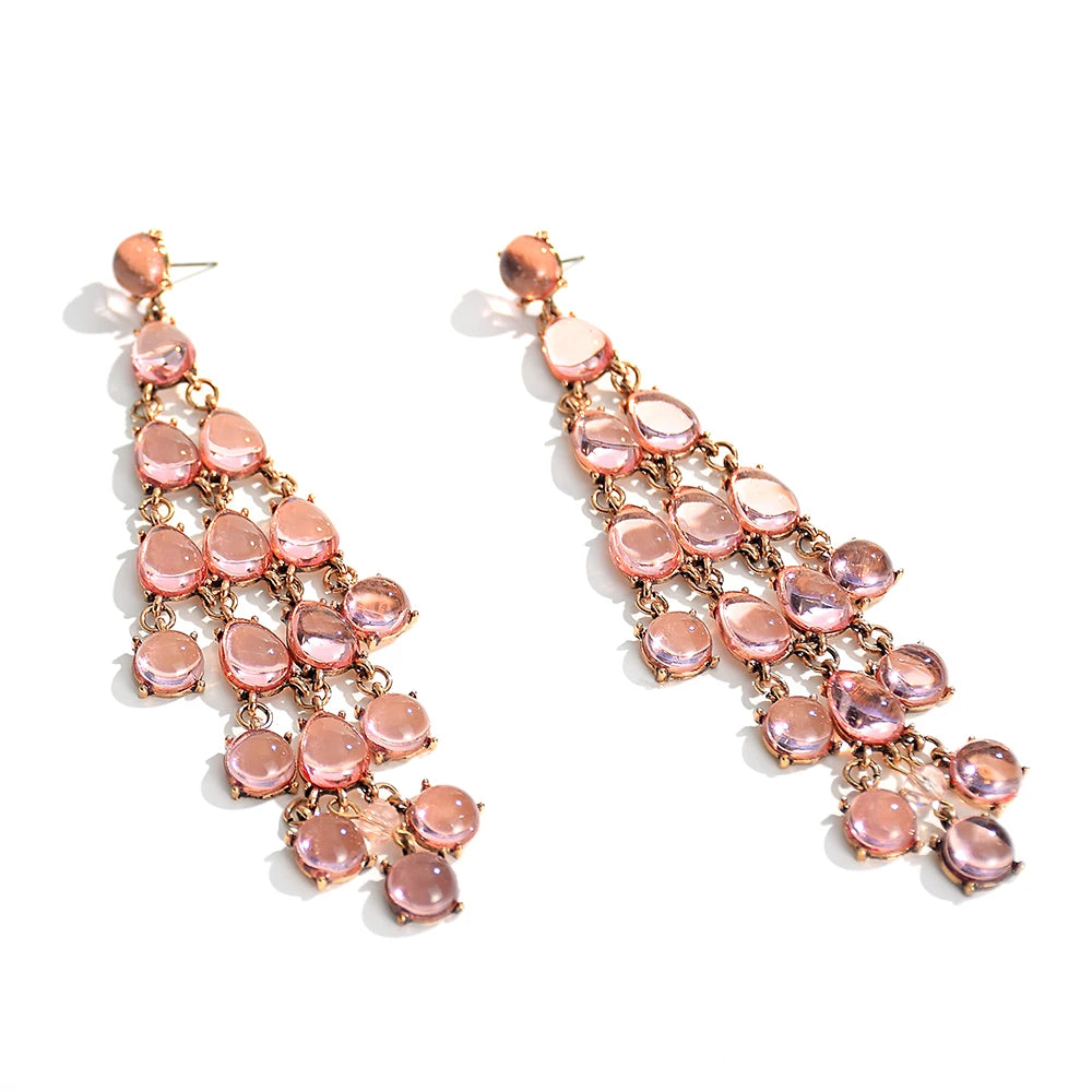 A pair of long tassel drop earrings with pink transparent resin crystals arranged in a cascading design.