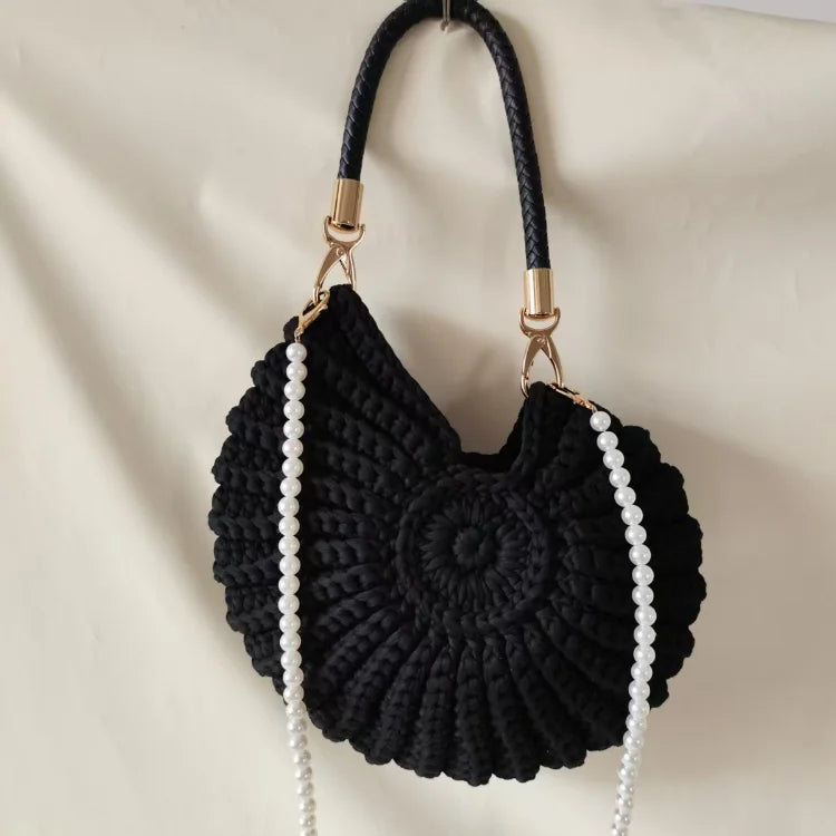 Fossil Seashell Bag in black soft woven cotton with shell shape by Montipi, styled in earthy beach tones – perfect for boho luxe, coastal chic, and summer outfits.
