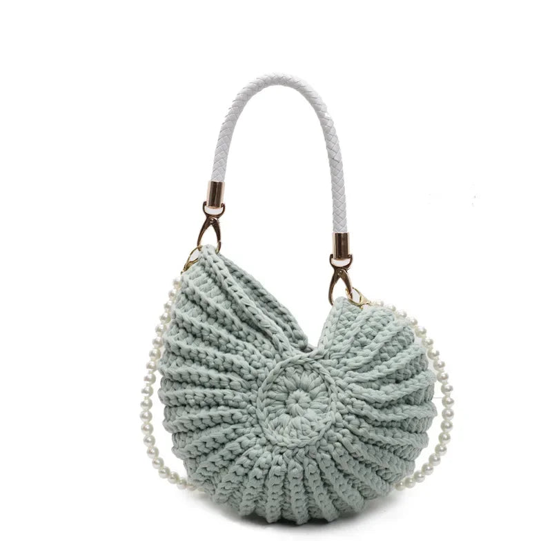 Fossil Seashell Bag in light blue soft woven cotton with shell shape by Montipi, styled in earthy beach tones – perfect for boho luxe, coastal chic, and summer outfits.