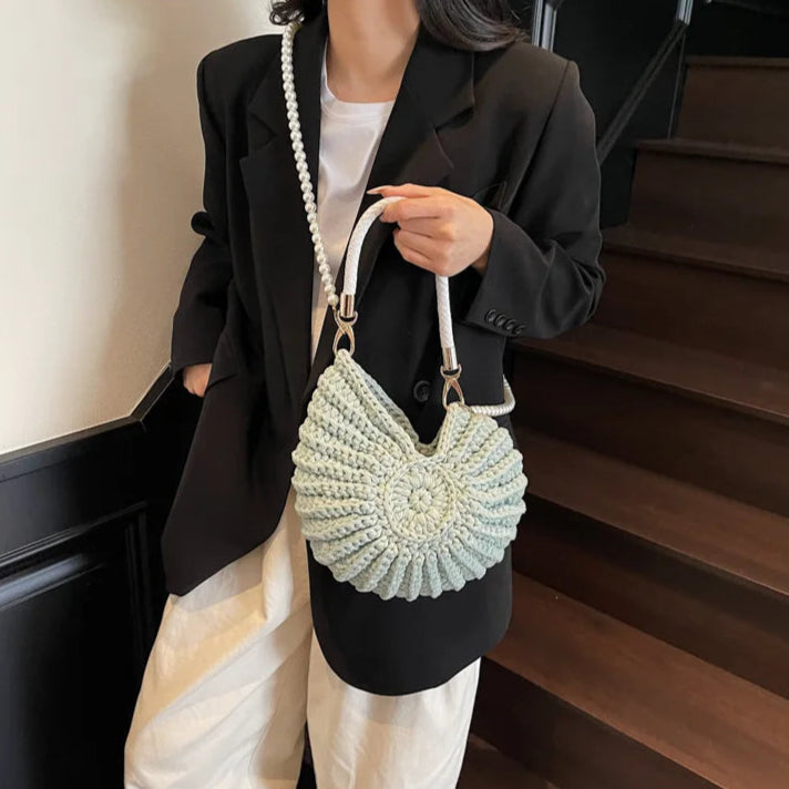 Fossil Seashell Bag in light blue soft woven cotton with shell shape by Montipi, styled in earthy beach tones – perfect for boho luxe, coastal chic, and summer outfits.