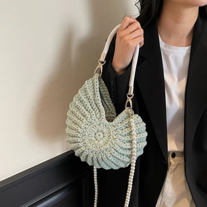 Fossil Seashell Bag in light blue soft woven cotton with shell shape by Montipi, styled in earthy beach tones – perfect for boho luxe, coastal chic, and summer outfits.