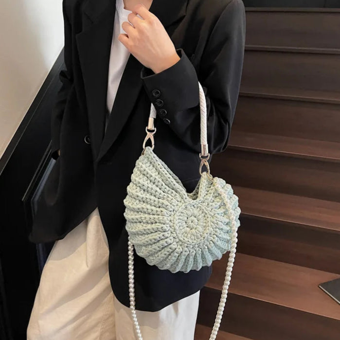 Fossil Seashell Bag in light blue soft woven cotton with shell shape by Montipi, styled in earthy beach tones – perfect for boho luxe, coastal chic, and summer outfits.