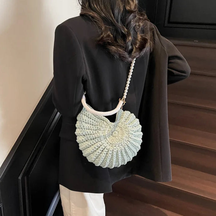 Fossil Seashell Bag in light blue soft woven cotton with shell shape by Montipi, styled in earthy beach tones – perfect for boho luxe, coastal chic, and summer outfits.