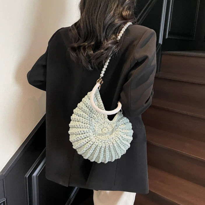 Fossil Seashell Bag in light blue soft woven cotton with shell shape by Montipi, styled in earthy beach tones – perfect for boho luxe, coastal chic, and summer outfits.