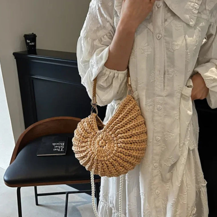 Fossil Seashell Bag in light brown soft woven cotton with shell shape by Montipi, styled in earthy beach tones – perfect for boho luxe, coastal chic, and summer outfits.