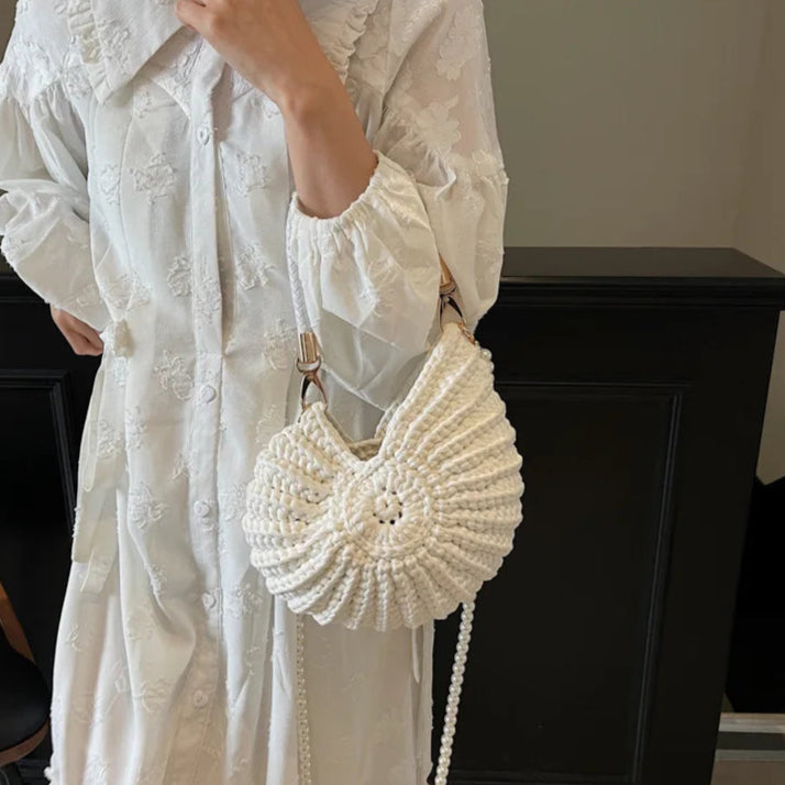 Fossil Seashell Bag in white soft woven cotton with shell shape by Montipi, styled in earthy beach tones – perfect for boho luxe, coastal chic, and summer outfits.