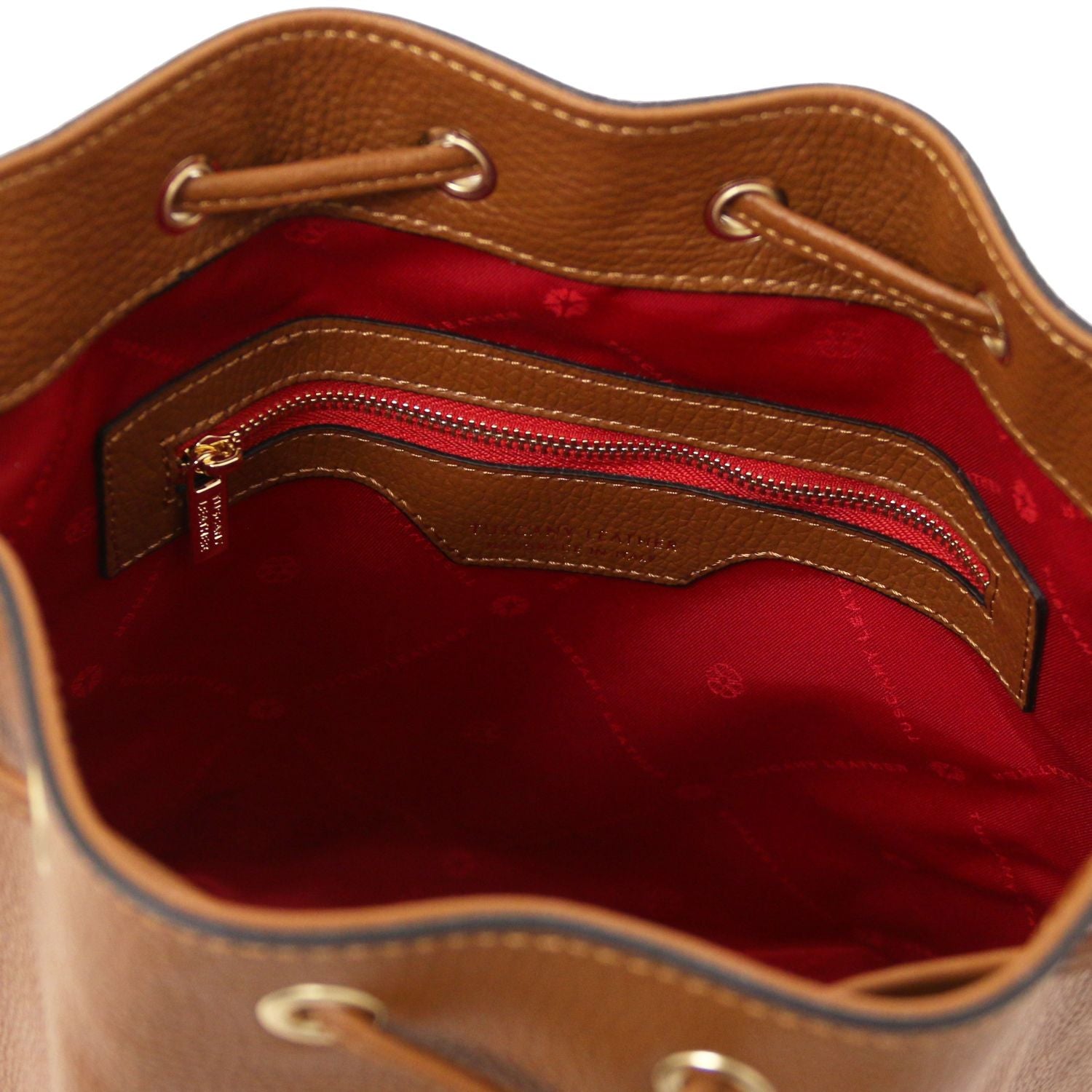 Interior view of the TL Leather Bucket Bag in cognac brown by Montipi Australia, featuring a bold red lining, spacious compartment, and secure internal zip pocket. Crafted from premium Italian pebbled leather with gold-tone hardware, this chic bucket bag blends elegance with everyday practicality.