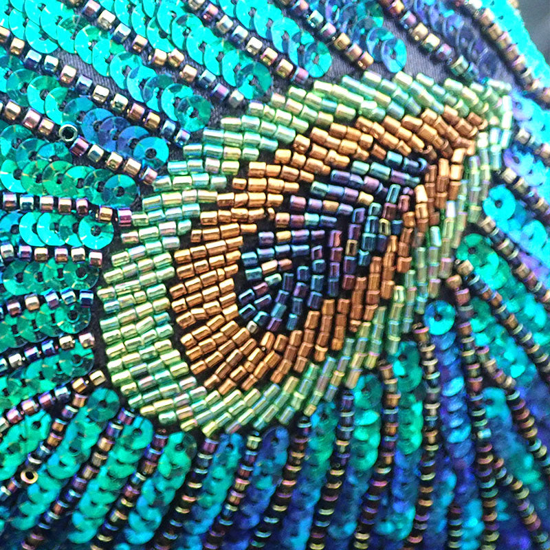 Close up on Teal Sequin Peacock Clutch unique beadwork design, showcasing gradient blue beads sheer copper brown beads and soft lemon beads reproducing the original peacock feather shape and design, extended by gorgeous pattern in vibrant teal green blue sequins bordered by lines of gradient blue beads to create a unique statement clutch bag elegant whimsical eclectic chic style by Montipi Australia