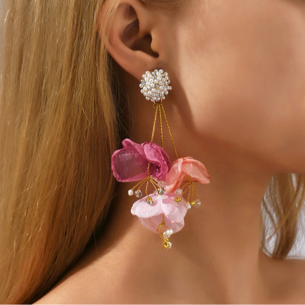 Close-up of a woman wearing elegant pink floral earrings with pearls