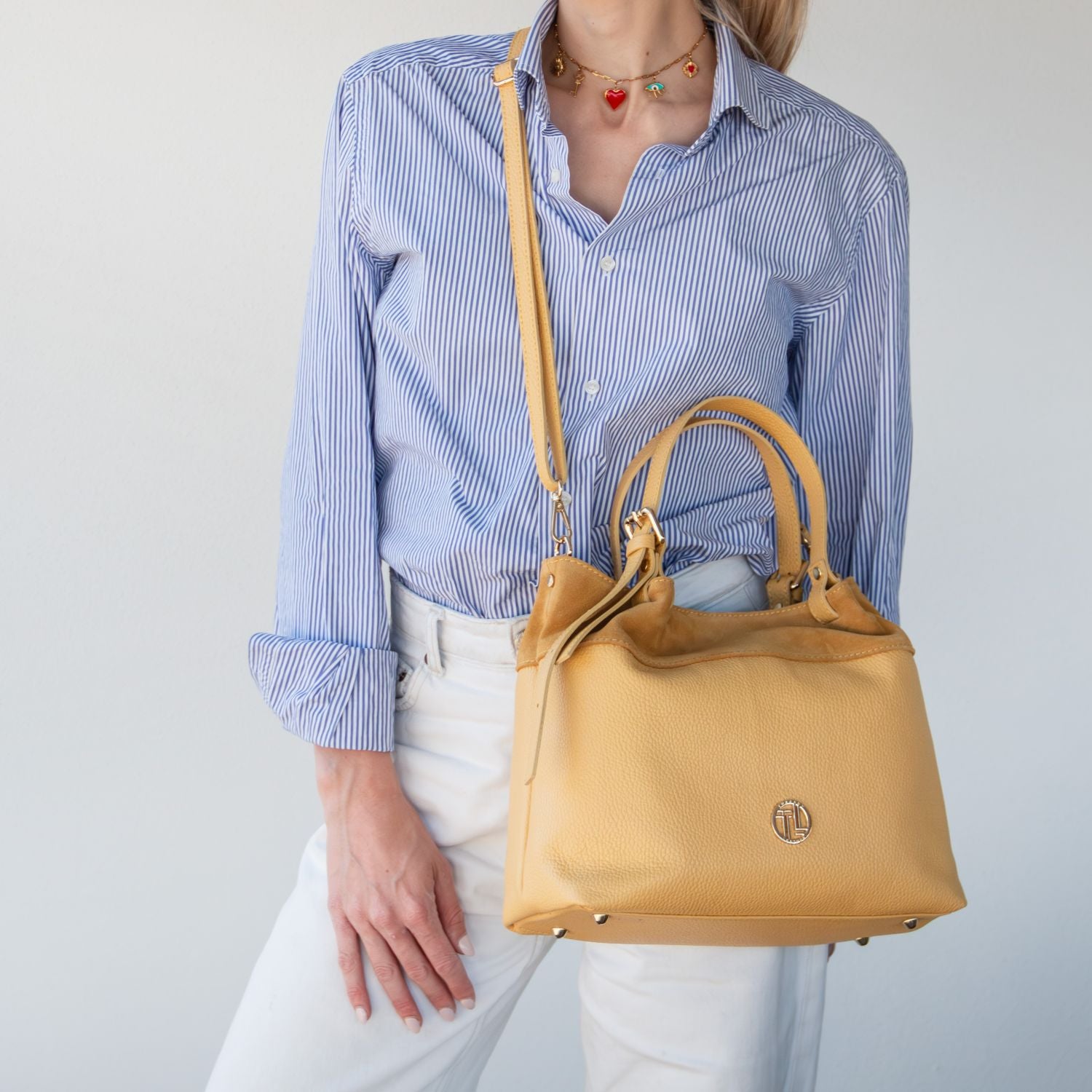 Yellow suede leather shoulder bag worn crossbody with adjustable strap
