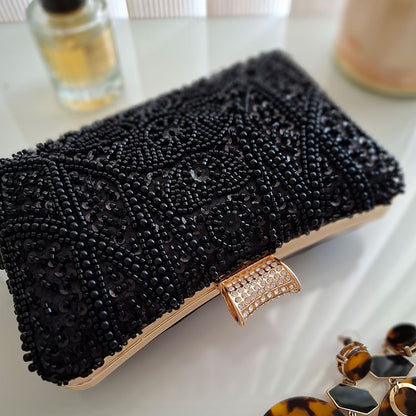 Elegant-Black-Beaded-Evening-Clutch-Bag-Pearl-Detailing-with-crystal-gold-hasp-closure-in-chic-background-with-perfume-and-earrings-by-Montipi-Australia