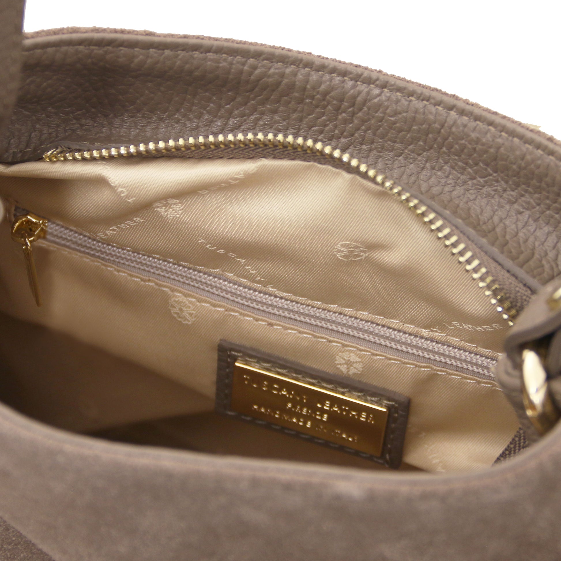 Close-up of the Nomad Dark Taupe Suede Leather Fringe Shoulder Bag interior showing logo tag, zip pocket, and smooth beige lining by Montipi.