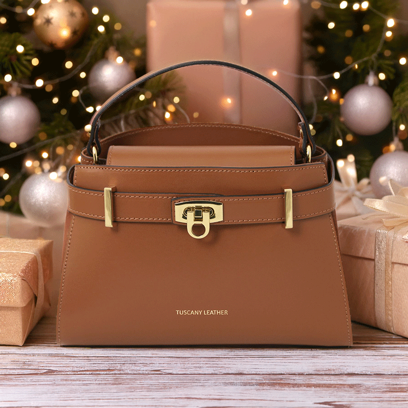 Elegant Maisy Luxe Leather Handbag in cognac with gold-tone hardware, styled among festive gift boxes and warm lights – premium Italian design by Montipi.