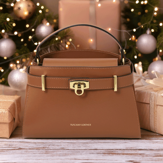 Elegant Maisy Luxe Leather Handbag in cognac with gold-tone hardware, styled among festive gift boxes and warm lights – premium Italian design by Montipi.