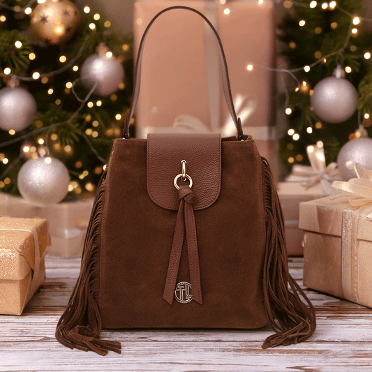 Nomad Suede Leather Fringe Shoulder Bag in brown suede and pebbled leather, styled among festive Christmas gifts and lights – a luxurious boho-luxe holiday gift by Montipi.