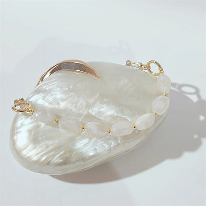 elegant and dreamy white pearl clutch with gold leaf decoration hasp closure and beaded handle with white stones, a dreamy mother of pearl effect white clutch  perfect for beach weddings by Montipi
