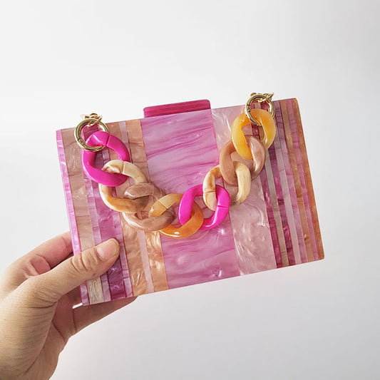 Pink Mirage Acrylic Clutch Bag featuring a striped pearl acrylic finish and colourful resin chain handle – perfect for weddings, resort chic, and boho luxe outfits.