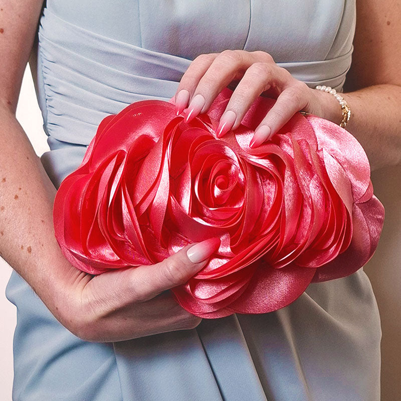 A delicate rose-shaped clutch bag with layered petal detailing in a soft, romantic hue. The elegant floral design mimics the texture of blooming petals, creating a timeless statement piece. Set against a refined backdrop, the clutch exudes femininity and sophistication, perfect for weddings, cocktail events, and special occasions. Rose Chic Petal Clutch Bag in rose pink by Montipi Australia