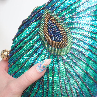 Close up on Teal Sequin Peacock Clutch with detailed beadwork design in feather shape, gold tone hardware and matching peacock nail art design in gold & blue, unique statement clutch bag elegant whimsical eclectic chic style created by Montipi Australia