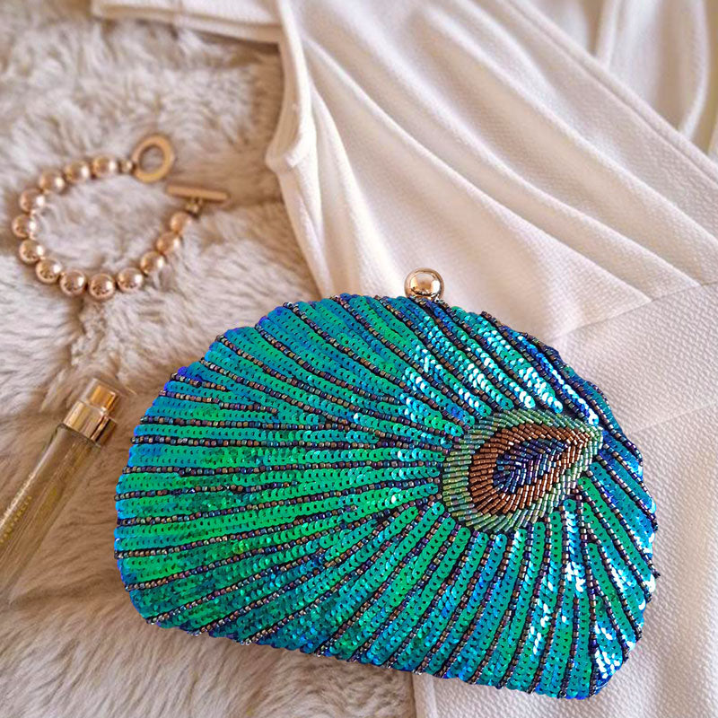 Aesthetic style inspo with Teal Sequin Peacock Clutch Bag, gold bracelet, gold tone perfume glass tube and cream white dress evening outfit style inspo by Montipi Australia
